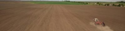 Farmer in tractor preparing land with seedbed cultivator as part of pre seeding activities in early spring season of agricultural works at farmlands. Drone photo