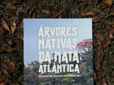 Cartilha Mata Atlântica Cartilha da Mata Atlântica com mudas nativas ao fundo.