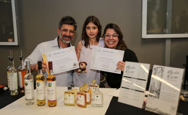 Eric Faustino e Cibele Silveira, produtores da Cachaça Maria Clara, de Itu, ao lado da filha Maria Clara, durante a premiação do II Concurso Estadual de Qualidade da Cachaça Paulista, em 2025. A Maria Clara Amburana conquistou Ouro, enquanto a Maria Clara Branquinha recebeu Prata.