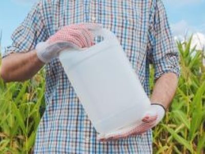 Farmer holding pesticide chemical jug in cornfield