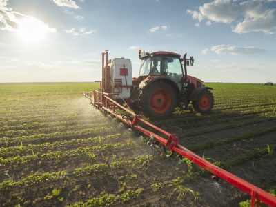 Tractor spraying pesticides at soy bean fields
