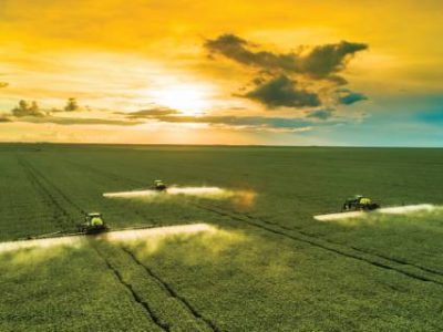 Agricultural sprayers making application at the end of the day with beautiful sunset