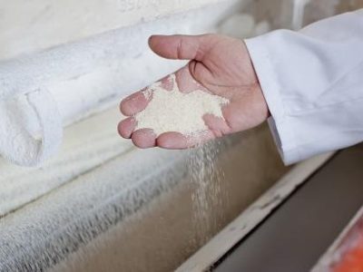 close up of the hand with ground flour of  wheat with Industrial mill in back ground