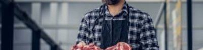 Portrait of a bearded meat man holds fresh cut meat.