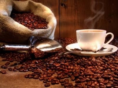 Coffee cup with burlap sack of roasted beans on rustic table